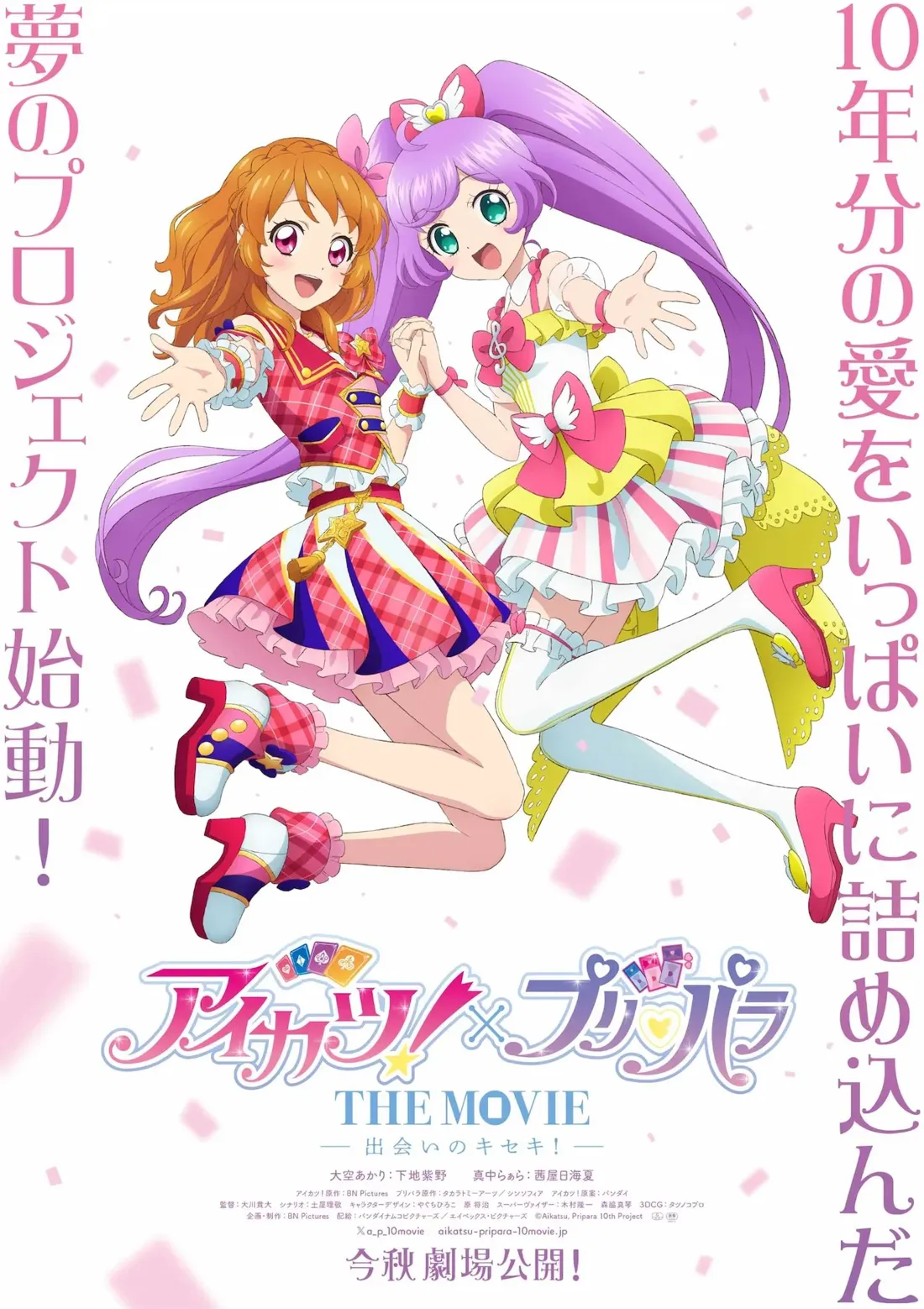 Promotional poster for the anime movie *Aikatsu! x Pripara: The Movie - The Miracle of Meeting!*  The poster features two female anime characters, holding hands, against a pink and white background with confetti.  The character on the left has bright orange hair styled in pigtails, wearing a red, pink, and white plaid dress with a gold star accent, and dark pink shoes with yellow accents. The character on the right has long purple hair styled in high ponytails and wears a light pink and yellow dress with pink and white stripes and white thigh-high socks. Both girls are in mid-air, dynamically posed, radiating a cheerful energy.  The movie title, 'アイカツ!×プリパラ THE MOVIE,' is prominently displayed at the bottom, along with Japanese text that translates to English promotional information including the release date. The artistic style is typical of bright, colorful anime promotional materials, characteristic of the *Aikatsu!* and *Pripara* franchises.
